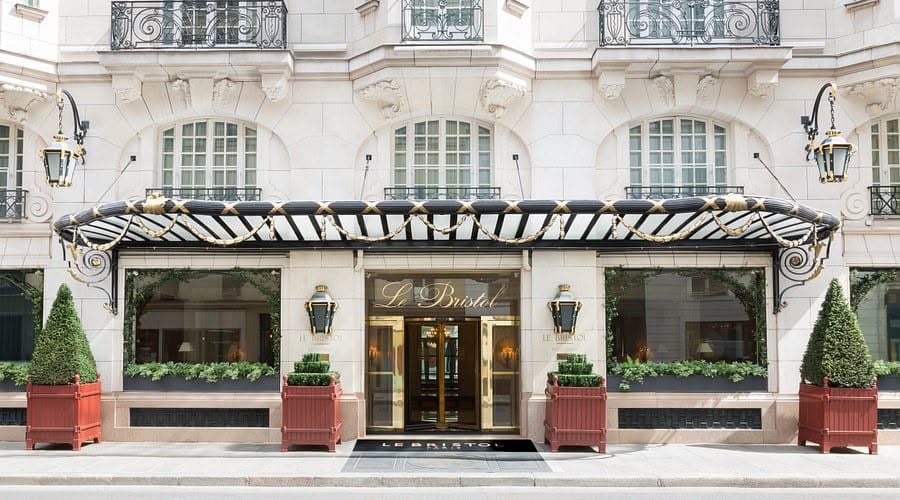 Façade du Bristol Paris : marquise noir et or, lanternes et buis taillés en bacs rouges