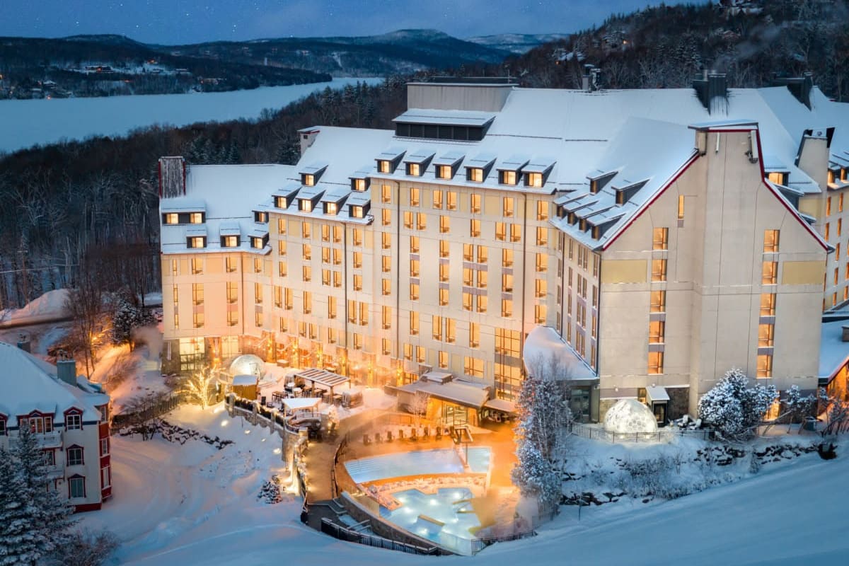 Le Fairmont Tremblant sous la neige, de nuit, au-dessus d’un lac gelé